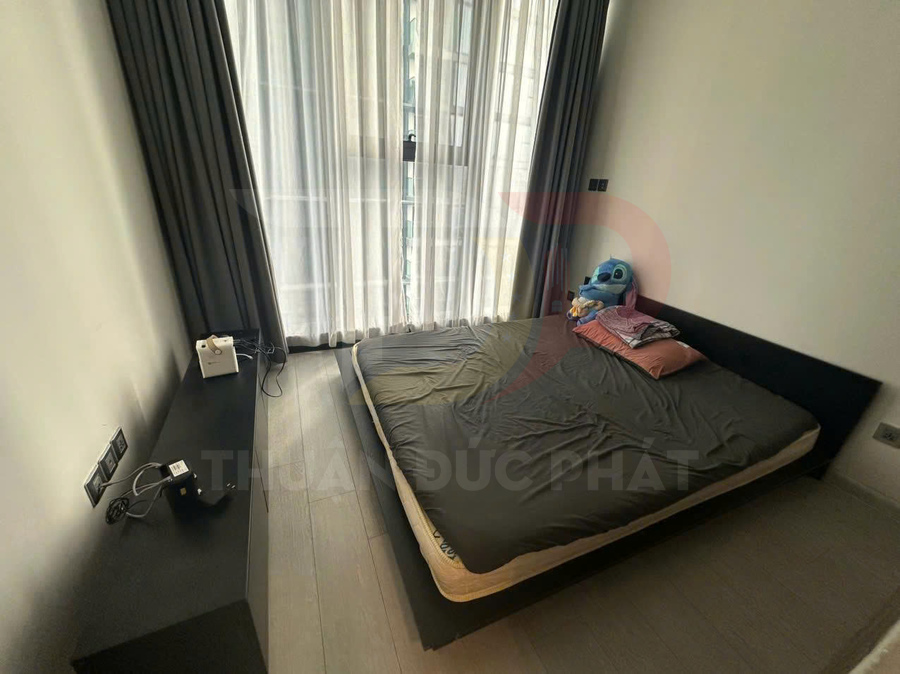 Phòng ngủ tối giản với giường nệm thấp màu đen cạnh cửa sổ lớn rèm xám