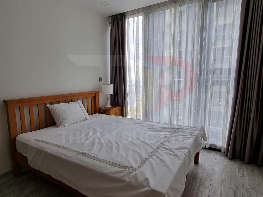 Phòng ngủ sáng với giường gỗ, drap trắng và cửa sổ kính lớn rèm xám