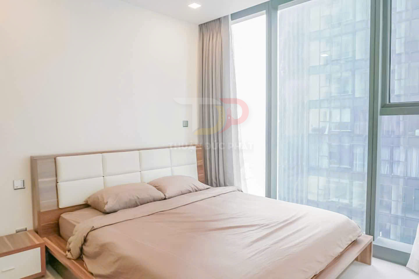 Giường ngủ gỗ hiện đại với ga gối màu be cạnh cửa sổ kính lớn tràn ngập ánh sáng tự nhiên