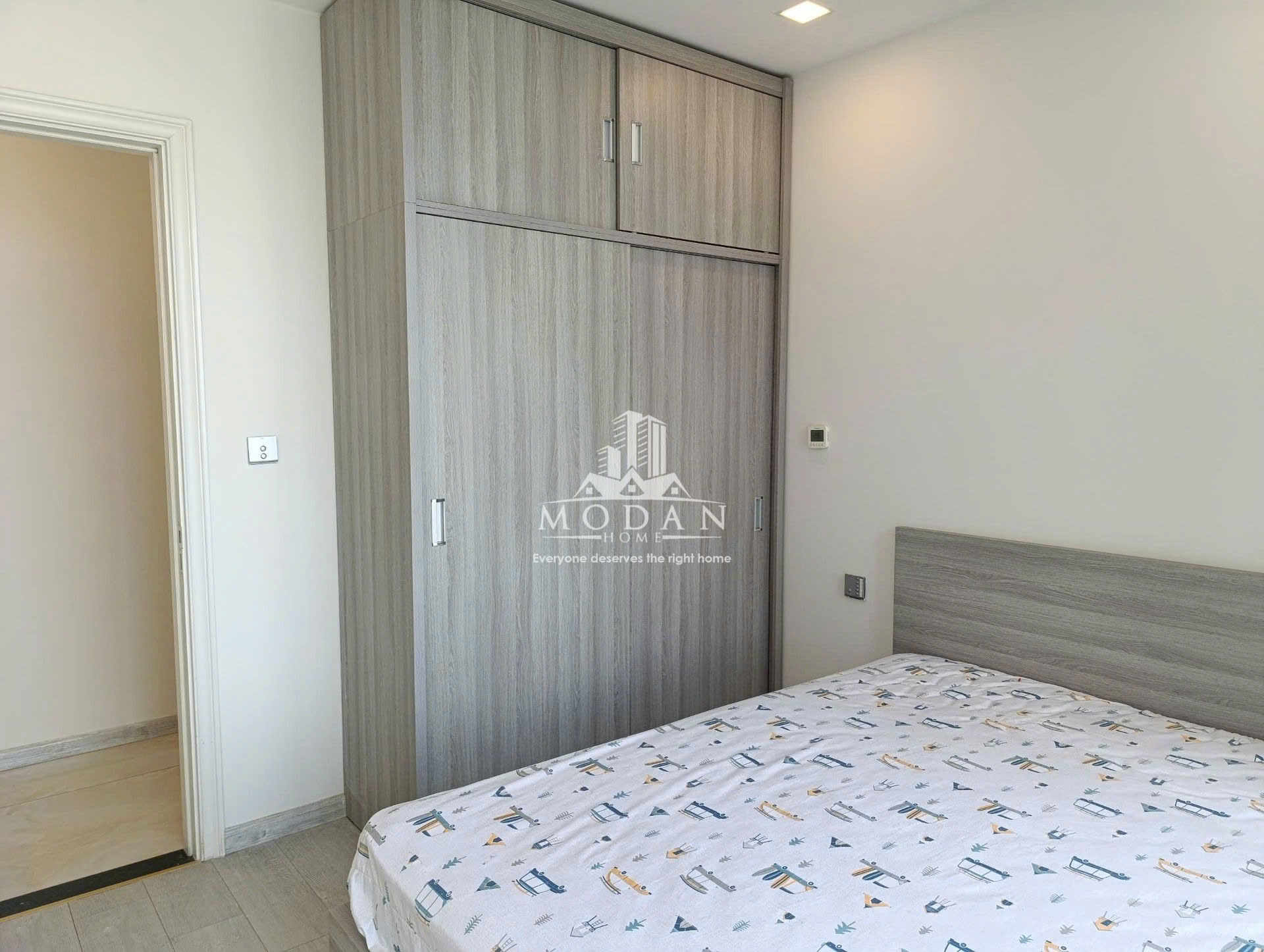 Phòng ngủ nhỏ với tủ quần áo gỗ âm tường và giường nệm ga họa tiết đơn giản