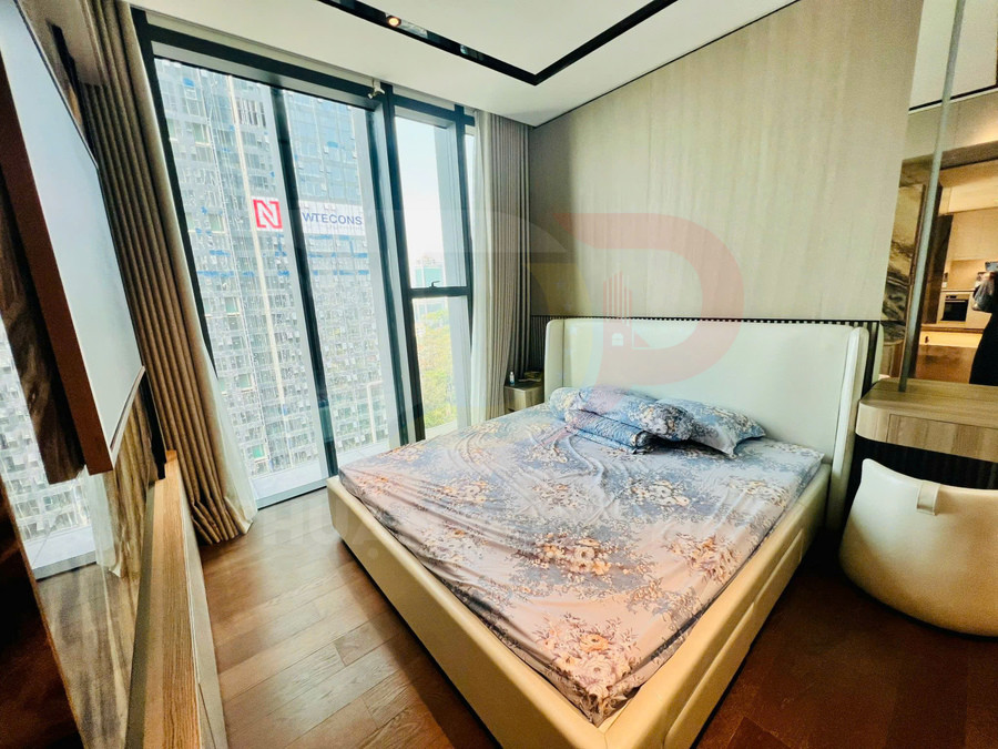 Giường ngủ bọc da màu kem với đầu giường cao, trải ga hoa văn pastel trong phòng ngủ hiện đại cao tầng