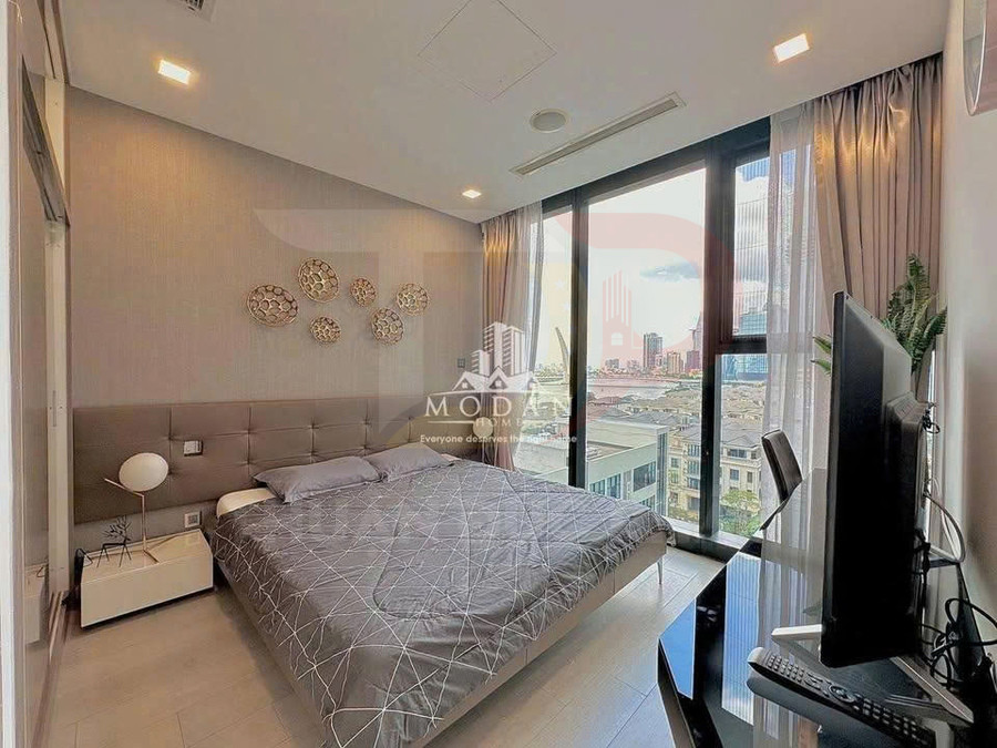 Phòng ngủ chung cư hiện đại với giường đôi, cửa kính lớn nhìn ra thành phố và bàn làm việc đặt màn hình máy tính