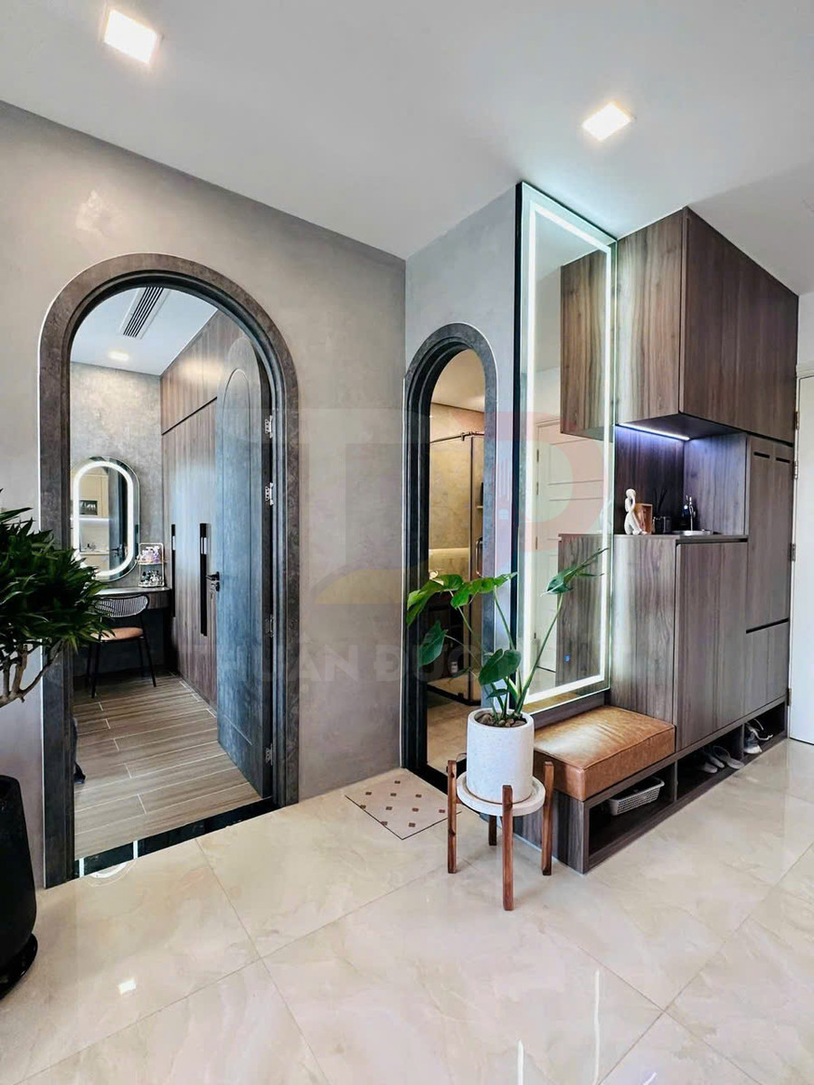 Sảnh căn hộ hiện đại với tủ gỗ âm tường, ghế bọc da, gương đèn LED và chậu cây trang trí