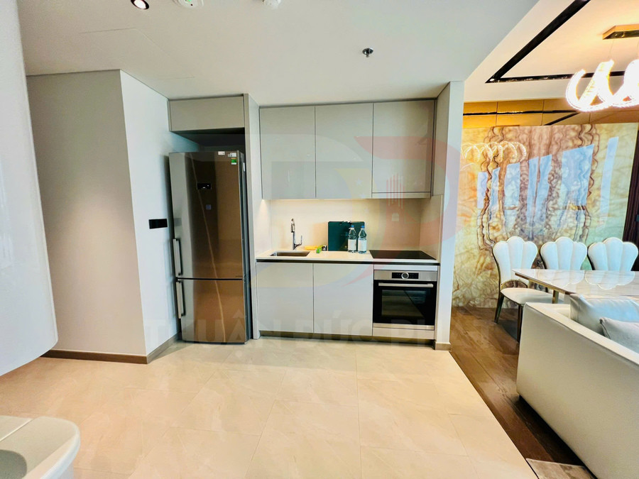 Tủ bếp hiện đại với tủ lạnh hai cửa, bếp từ, lò nướng âm tủ và mặt bàn đá trắng