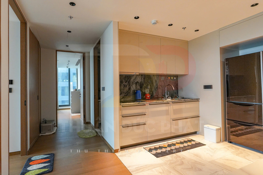 Gian bếp nhỏ hiện đại với tủ bếp màu be, mặt đá hoa cương và tủ lạnh inox trong căn hộ cao cấp