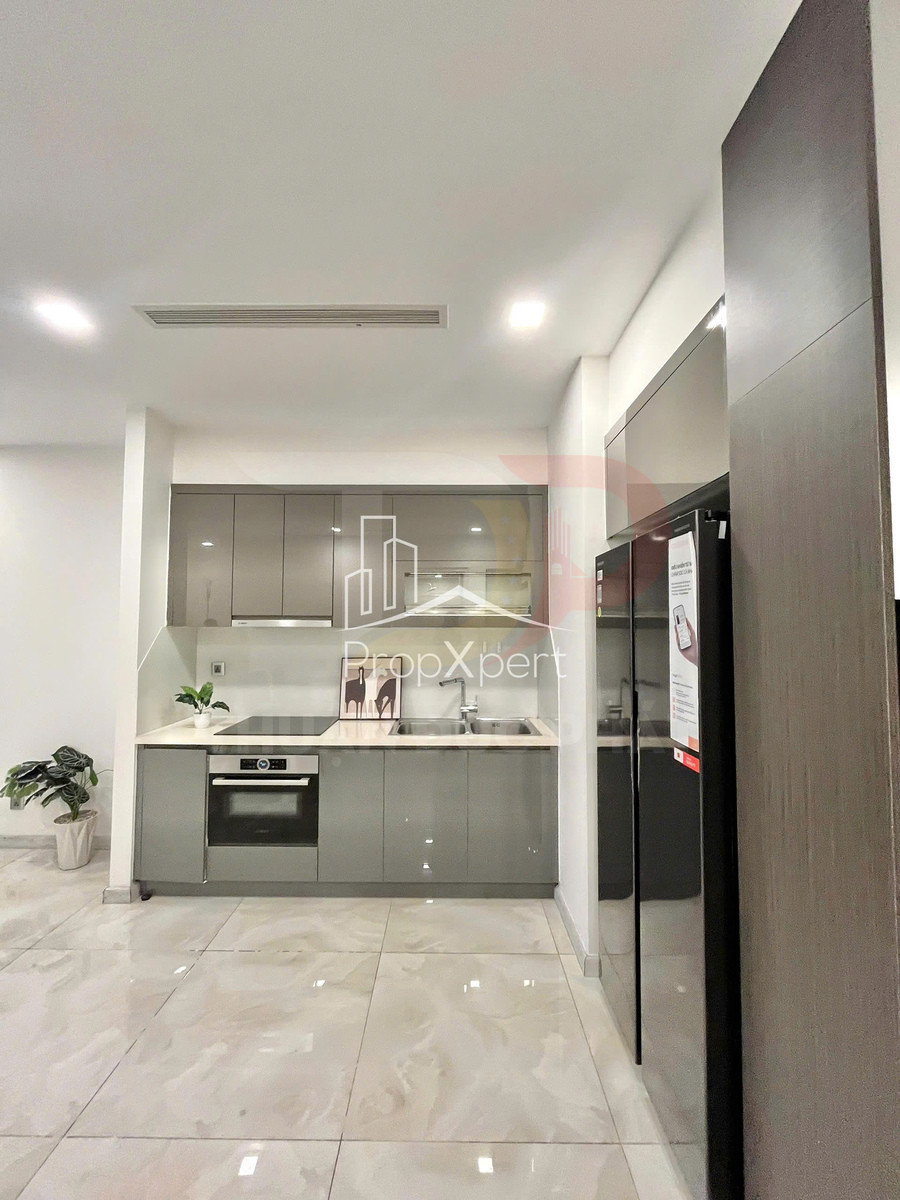 Gian bếp hiện đại với tủ bếp màu xám, bếp điện âm, lò nướng và bồn rửa inox gọn gàng