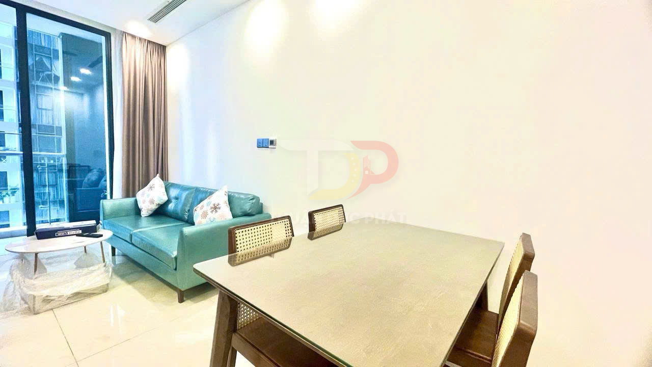 Bàn ăn gỗ mặt kính cạnh sofa da màu xanh trong phòng khách căn hộ hiện đại có cửa kính lớn