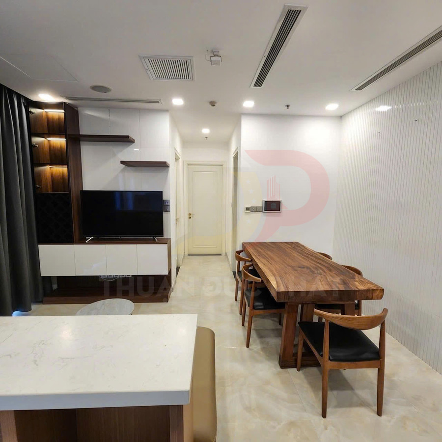 Bàn ăn gỗ nguyên tấm kèm ghế tựa lưng trong phòng khách căn hộ hiện đại có kệ tivi gỗ và tủ treo tường