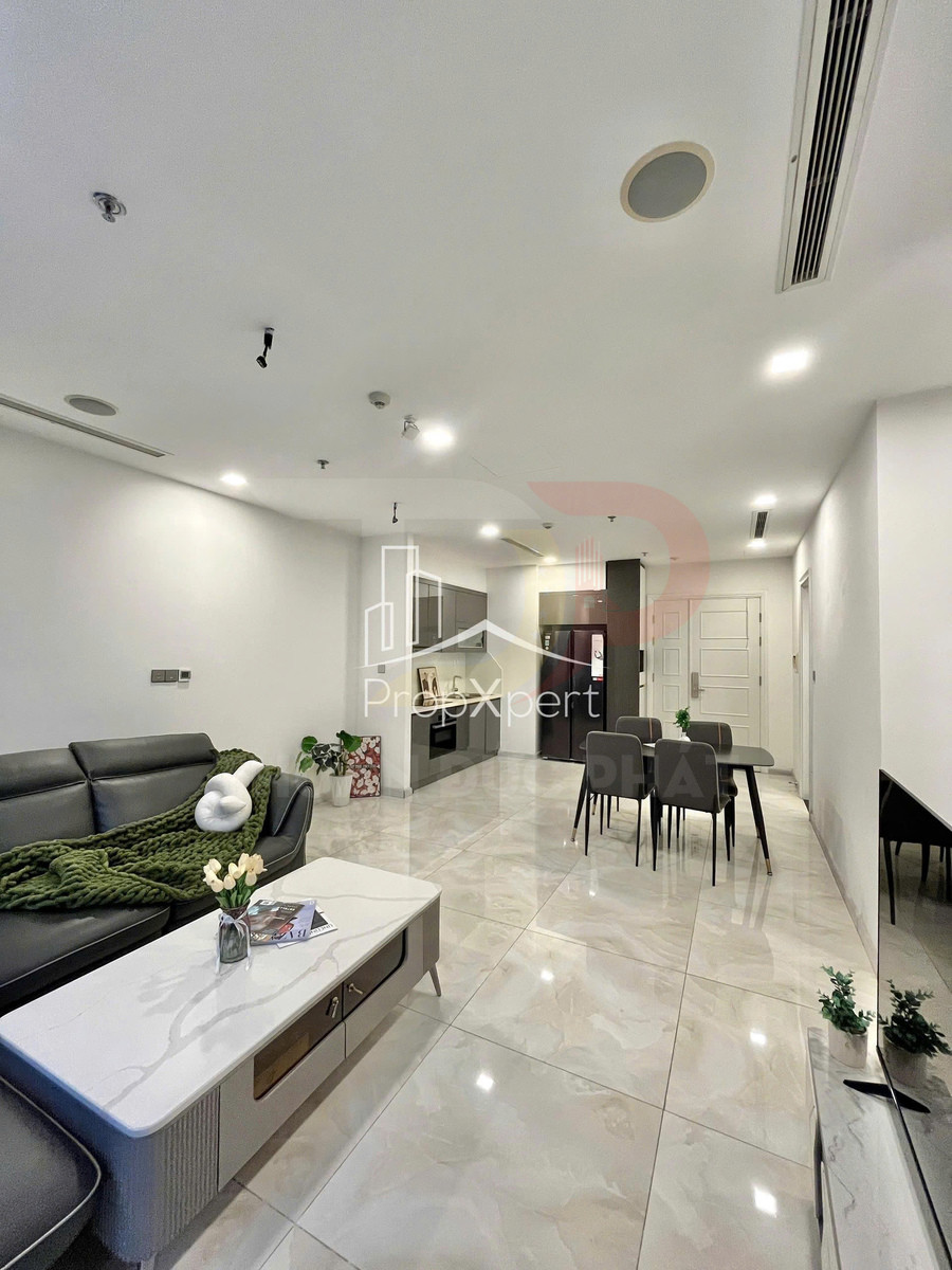 Phòng khách căn hộ hiện đại với sofa da đen, bàn trà đá, bếp và bàn ăn liền kề sáng sạch