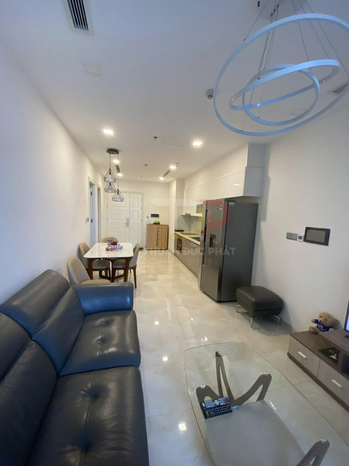 Phòng khách căn hộ hiện đại với sofa da, bàn kính, bàn ăn và bếp liền kề nội thất tối giản