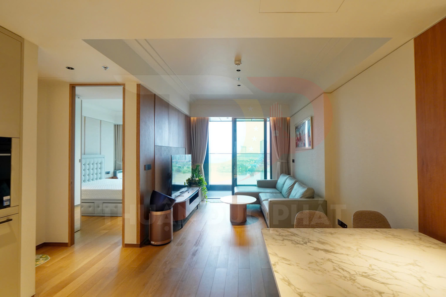 Phòng khách căn hộ hiện đại với sofa, bàn trà gỗ, tivi và cửa kính lớn nhìn ra ban công