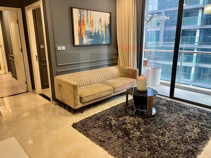 Sofa vải màu be trong phòng khách hiện đại cạnh bàn trà tròn và cửa kính lớn nhìn ra ban công