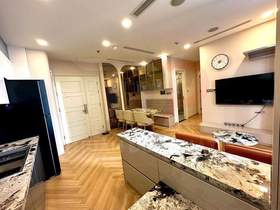 Căn hộ hiện đại với bếp mặt đá hoa cương, bàn ăn ghế bọc nệm và phòng khách có tivi treo tường