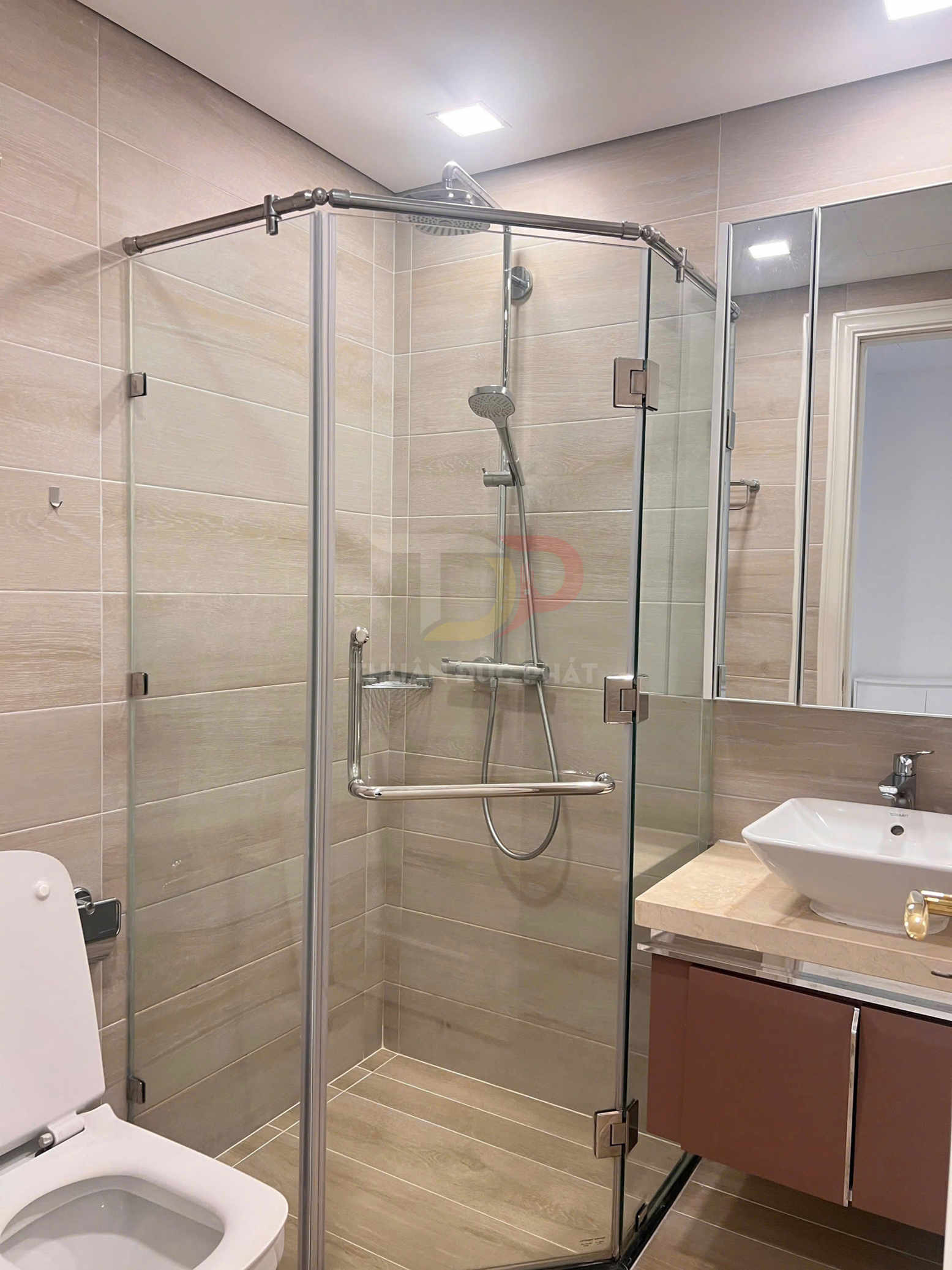 Phòng tắm hiện đại với buồng tắm kính đứng, vòi sen inox, bồn cầu và lavabo đặt trên tủ gỗ