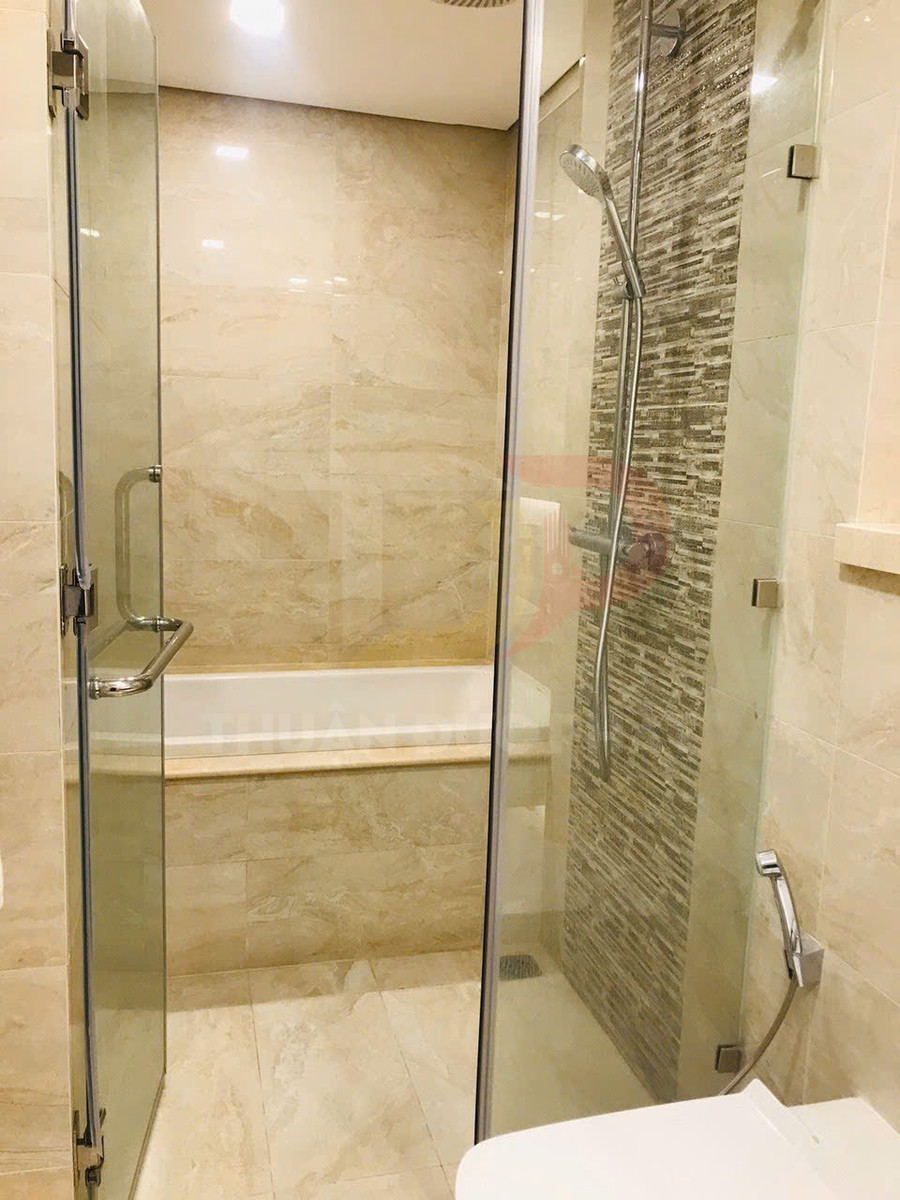 Phòng tắm hiện đại với vách kính, vòi sen đứng và bồn tắm ốp đá marble sáng màu