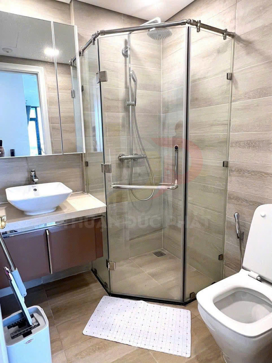 Phòng tắm hiện đại với buồng tắm kính góc, vòi sen cây inox và bồn cầu sứ trắng