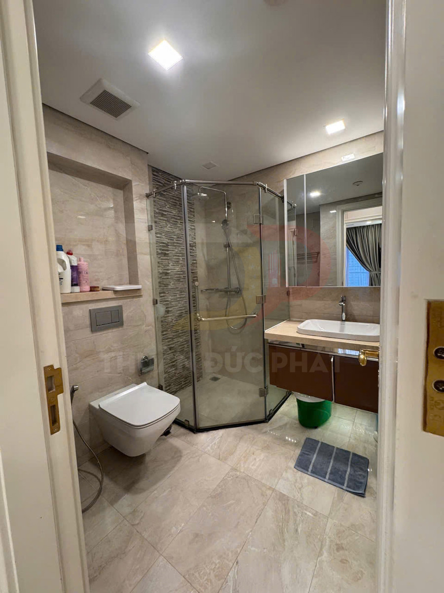 Phòng tắm hiện đại với bồn cầu treo tường, buồng tắm kính đứng và lavabo đặt trên tủ gỗ