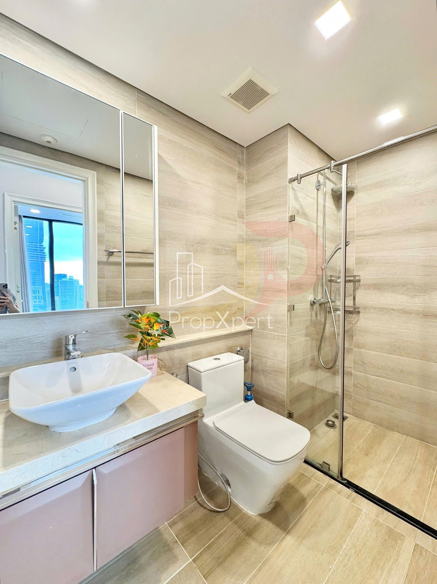 Phòng tắm hiện đại với bồn rửa mặt sứ, bồn cầu và buồng tắm kính đứng lát gạch sáng màu