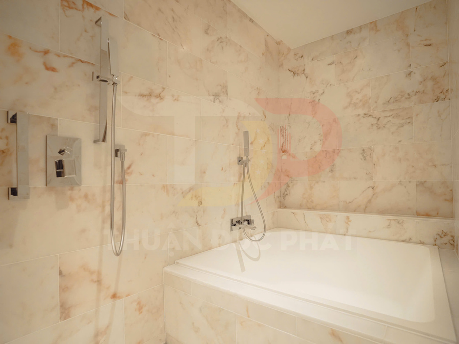 Bồn tắm nằm kèm vòi sen tay hiện đại trong phòng tắm ốp gạch đá marble sáng