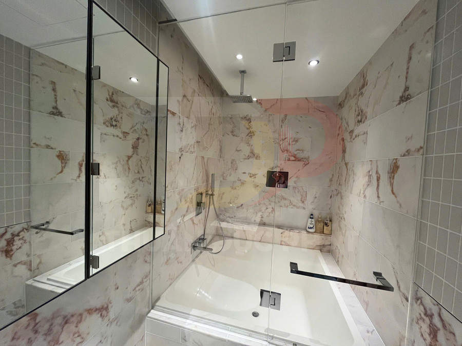 Bồn tắm kính hiện đại với vòi sen trần và tường ốp gạch giả đá marble sang trọng