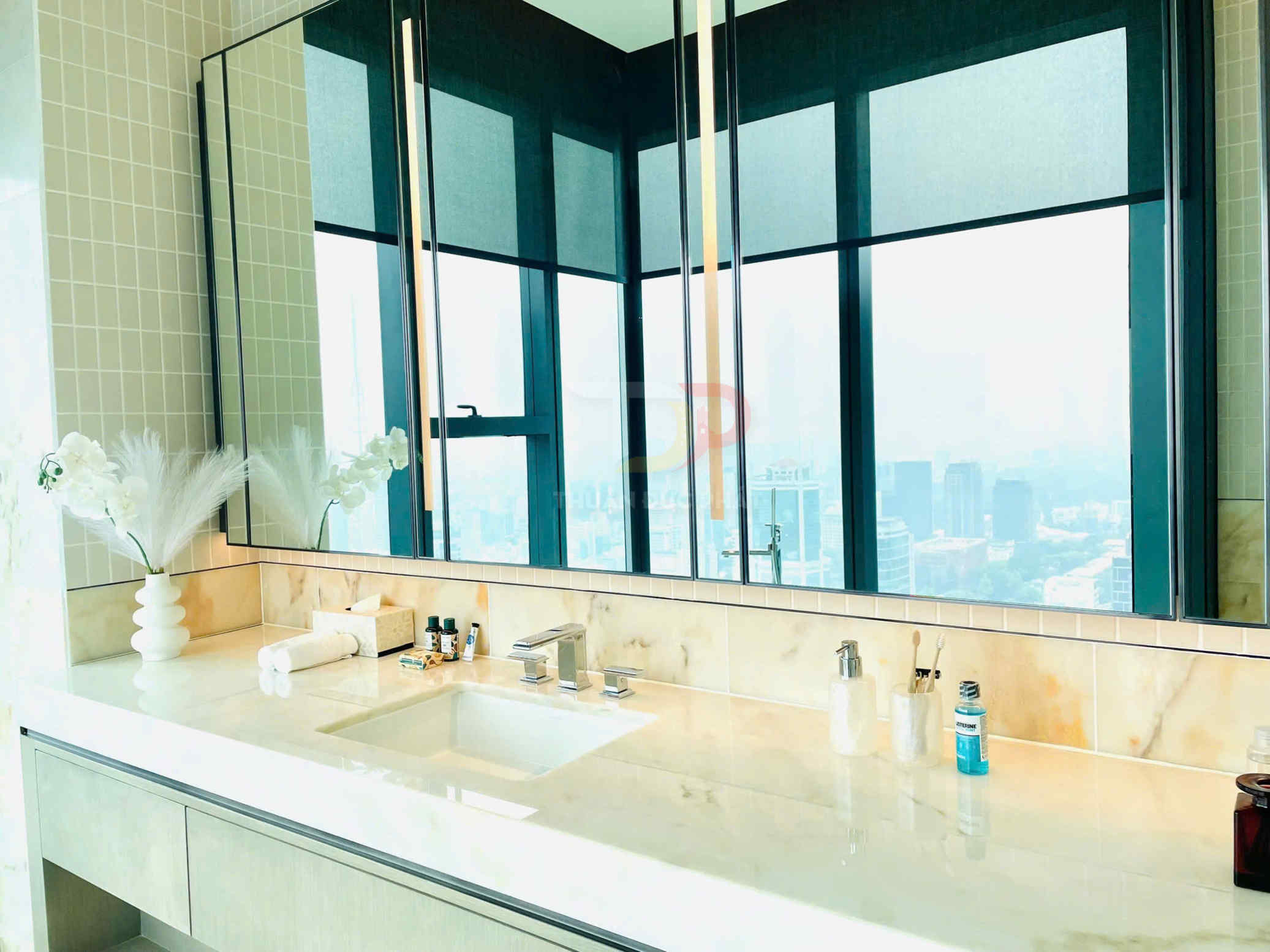 Bồn rửa mặt đá cẩm thạch cao cấp với vòi nước inox và đồ dùng vệ sinh bày gọn gàng trong phòng tắm sang trọng