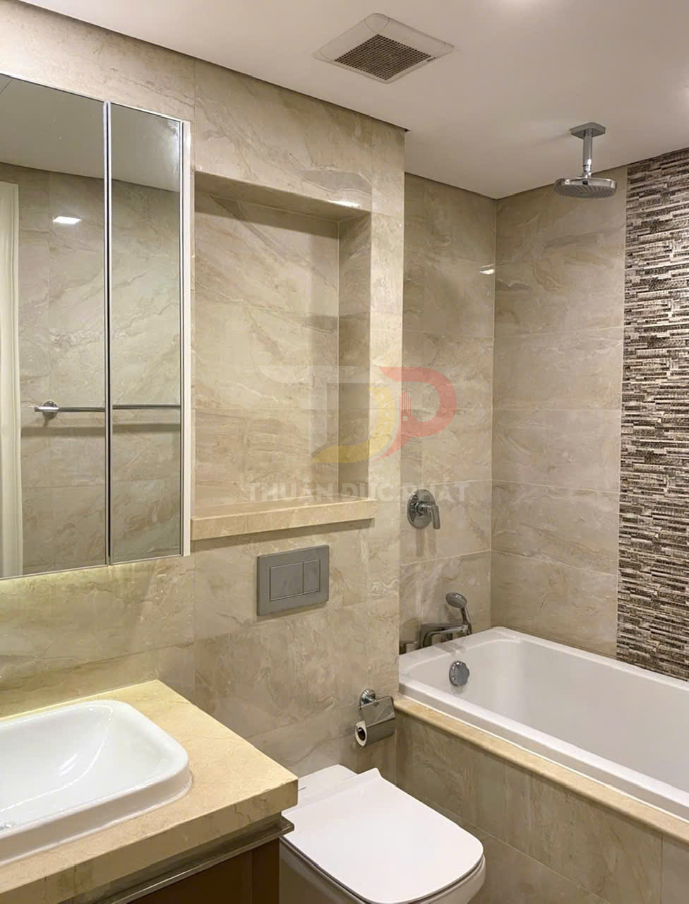 Phòng tắm hiện đại với bồn tắm nằm, bồn rửa mặt, bồn cầu và gạch ốp tường đá marble sáng