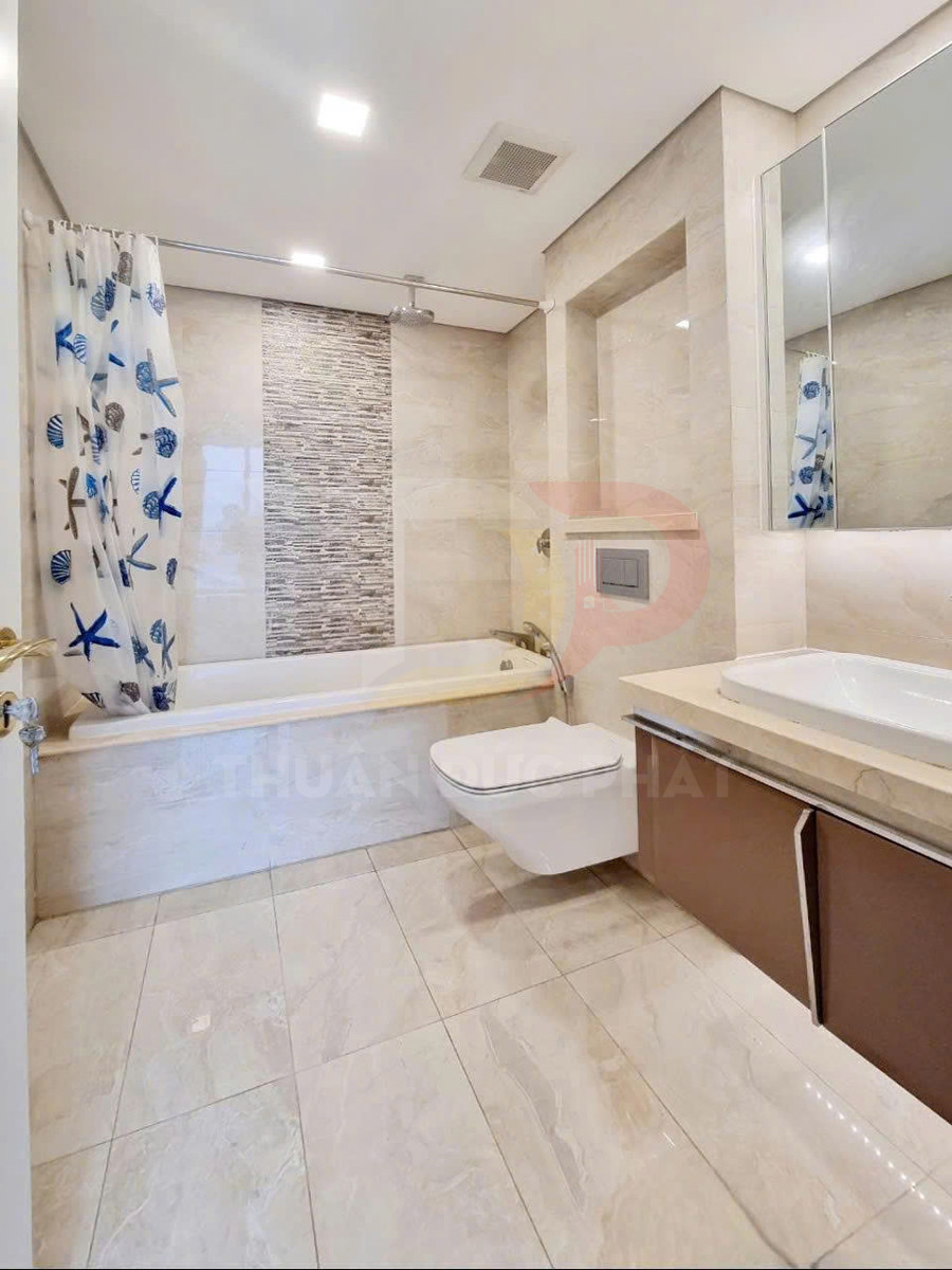 Phòng tắm hiện đại với bồn tắm nằm, bồn cầu treo tường và lavabo đặt trên tủ gỗ màu nâu