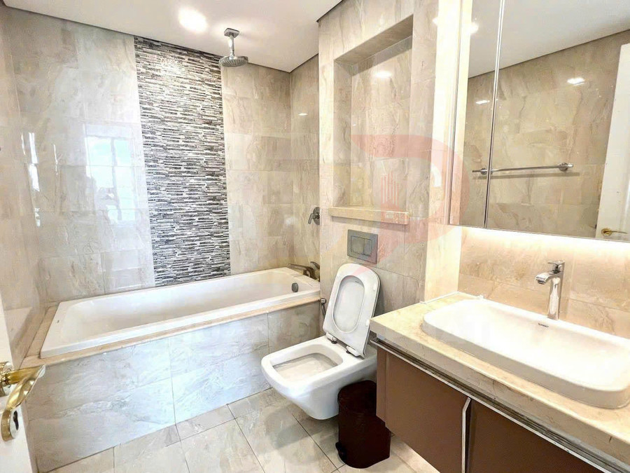 Phòng tắm hiện đại với bồn tắm nằm, bồn cầu treo tường và lavabo đá kèm gương lớn
