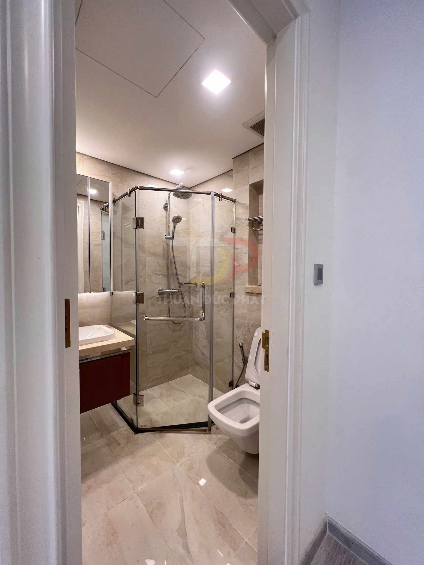 Phòng tắm hiện đại với buồng tắm kính, bồn cầu và lavabo đá sáng màu