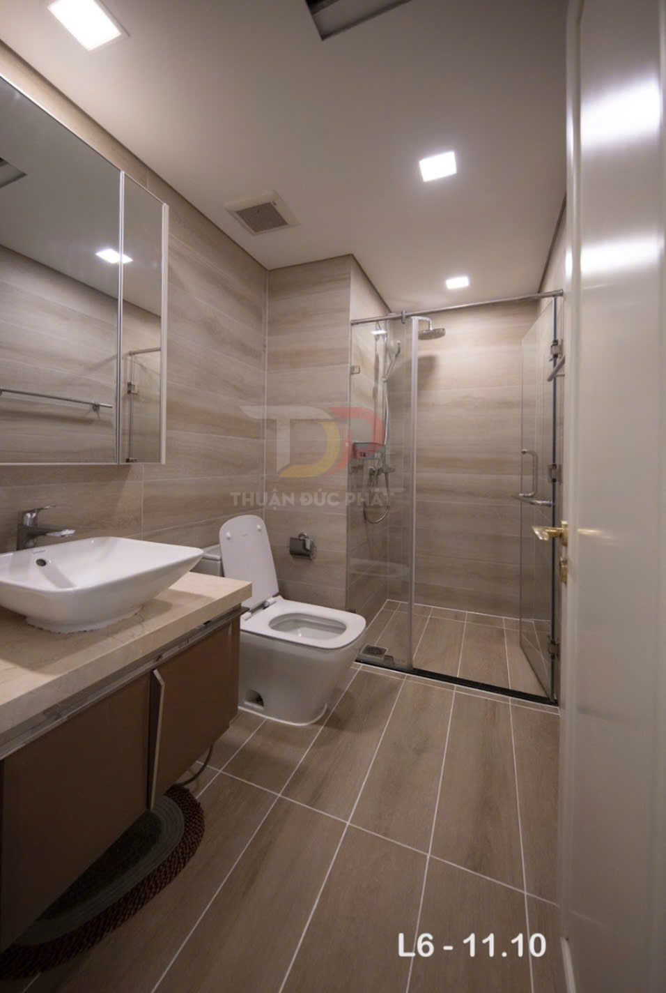 Phòng tắm hiện đại với bồn cầu, lavabo đặt bàn và buồng tắm kính cửa trượt, ốp gạch giả gỗ