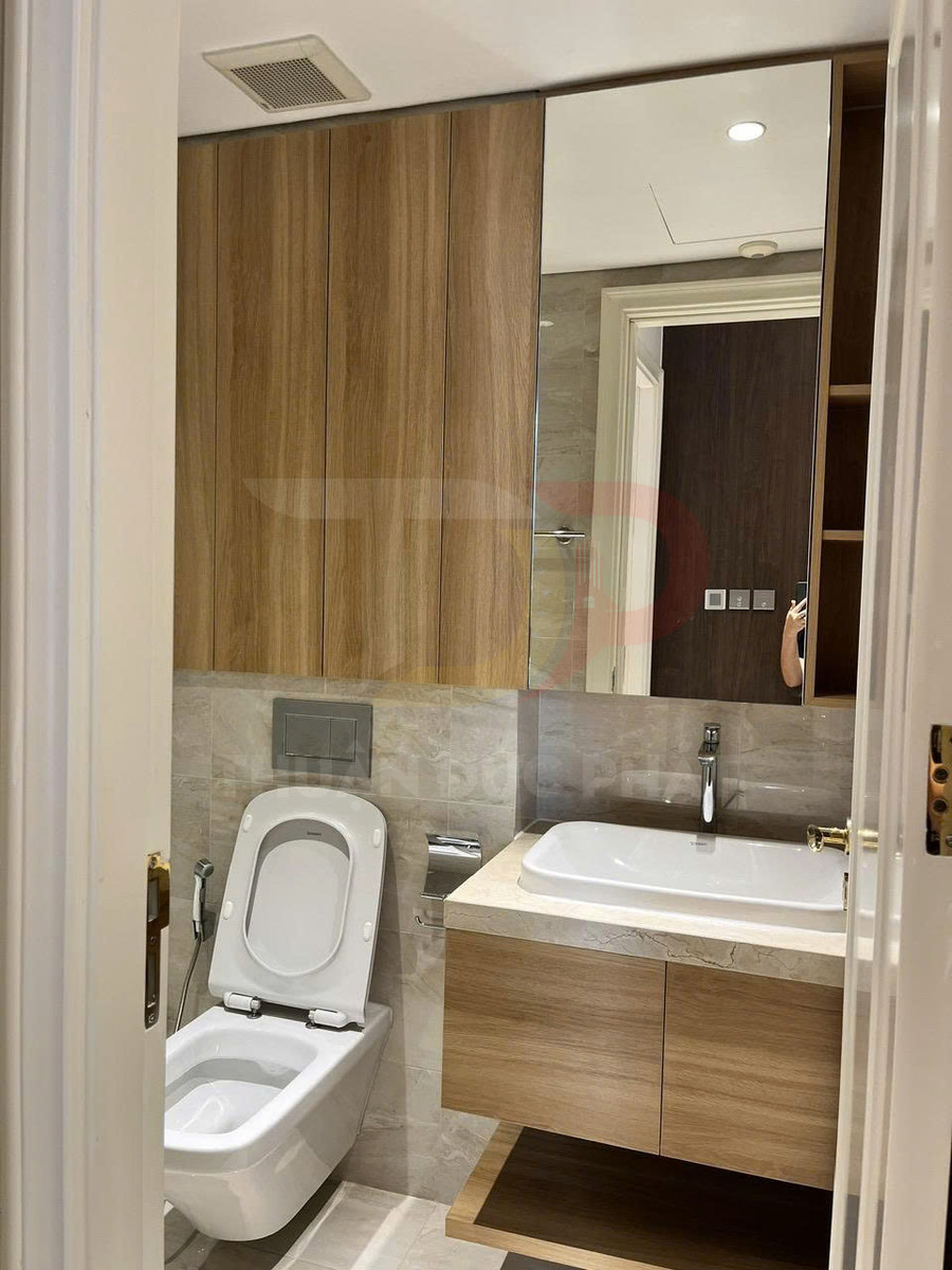 Nhà vệ sinh hiện đại với bồn cầu treo tường, vòi xịt và lavabo đặt trên tủ gỗ sang trọng