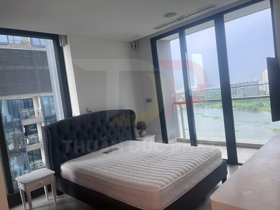 Phòng ngủ chung cư với giường nệm đôi cạnh cửa kính lớn nhìn ra hồ và thành phố