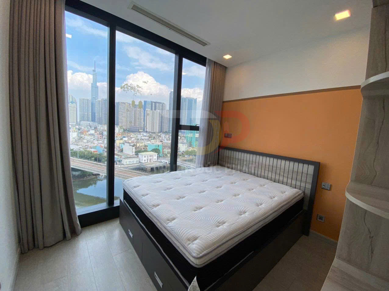 Giường ngủ hiện đại với nệm dày cạnh cửa kính lớn view thành phố ban ngày