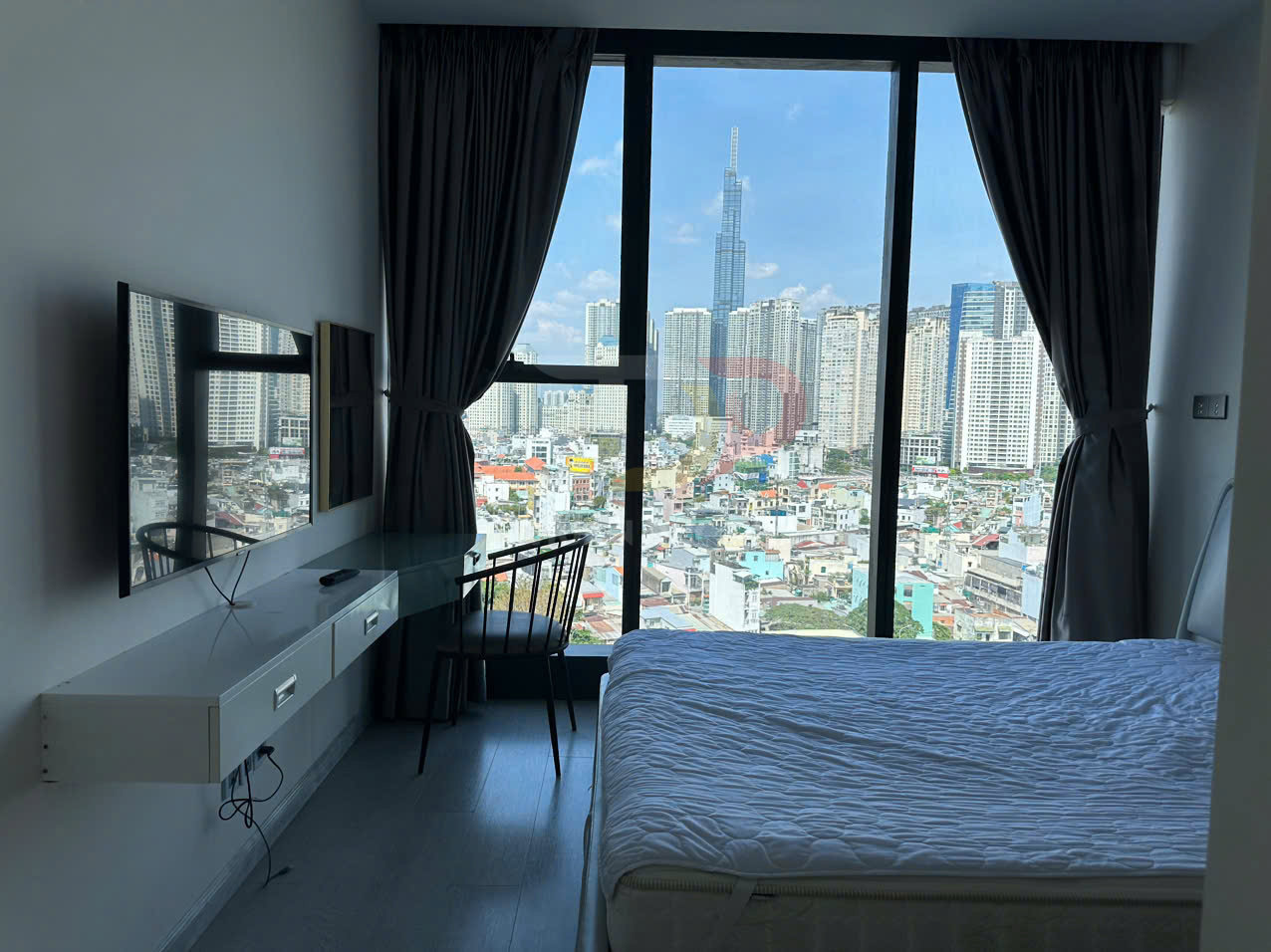 Phòng ngủ chung cư hiện đại với giường đôi, bàn làm việc, tivi treo tường và cửa kính lớn nhìn ra thành phố