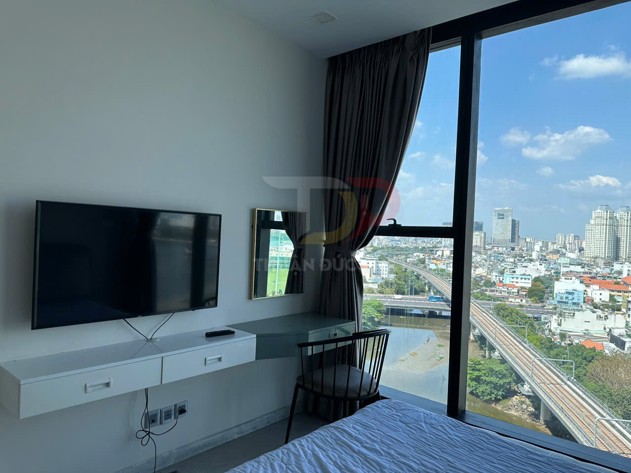 Phòng ngủ chung cư hiện đại với tivi treo tường, bàn làm việc cạnh cửa sổ lớn view thành phố
