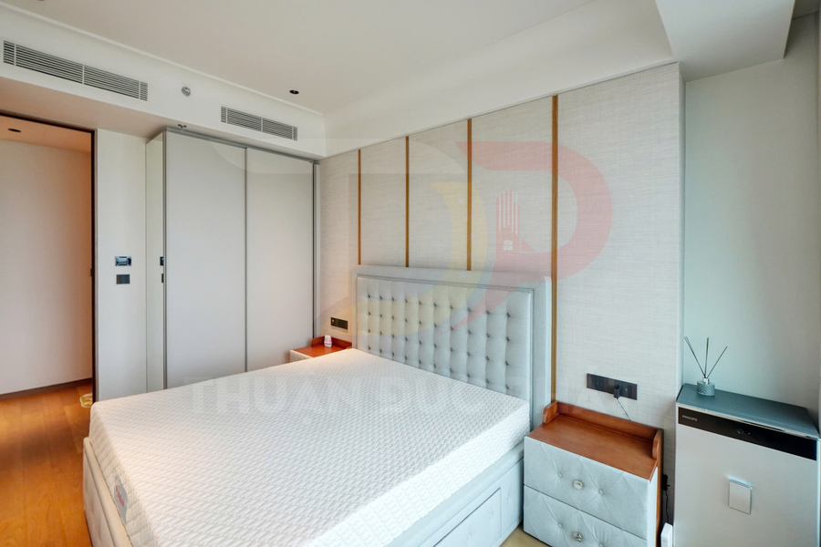 Phòng ngủ hiện đại với giường bọc nệm màu xám, tủ quần áo cửa lùa và hai tủ đầu giường gỗ