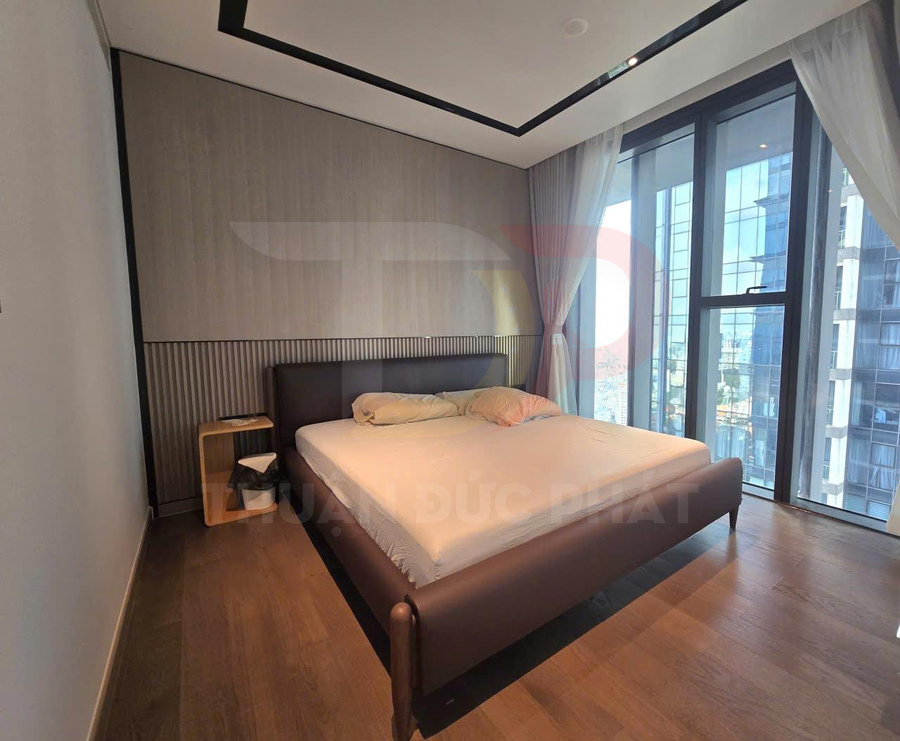 Giường ngủ bọc da hiện đại trong phòng ngủ có cửa kính lớn và rèm trắng