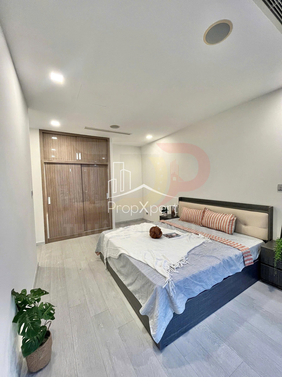 Phòng ngủ hiện đại với giường đôi bọc nệm, tủ quần áo gỗ âm tường và sàn gỗ sáng màu