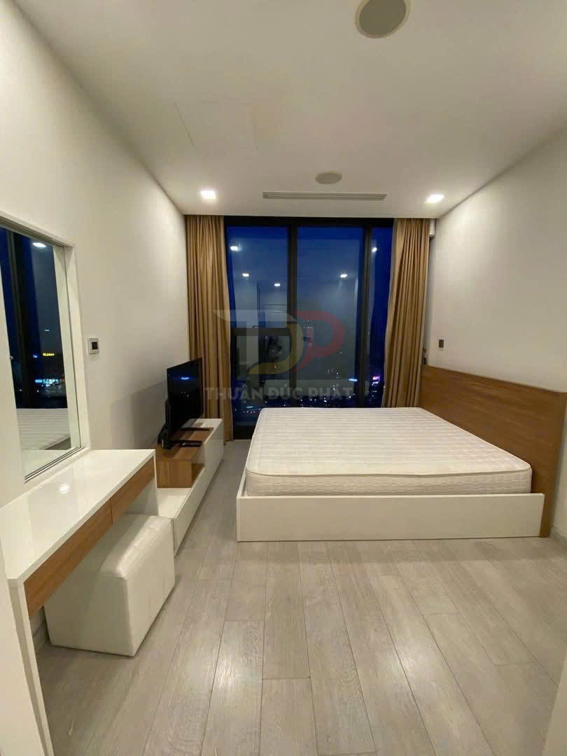 Phòng ngủ hiện đại với giường ngủ gỗ màu trắng, nệm dày và bàn trang điểm cạnh cửa sổ kính lớn