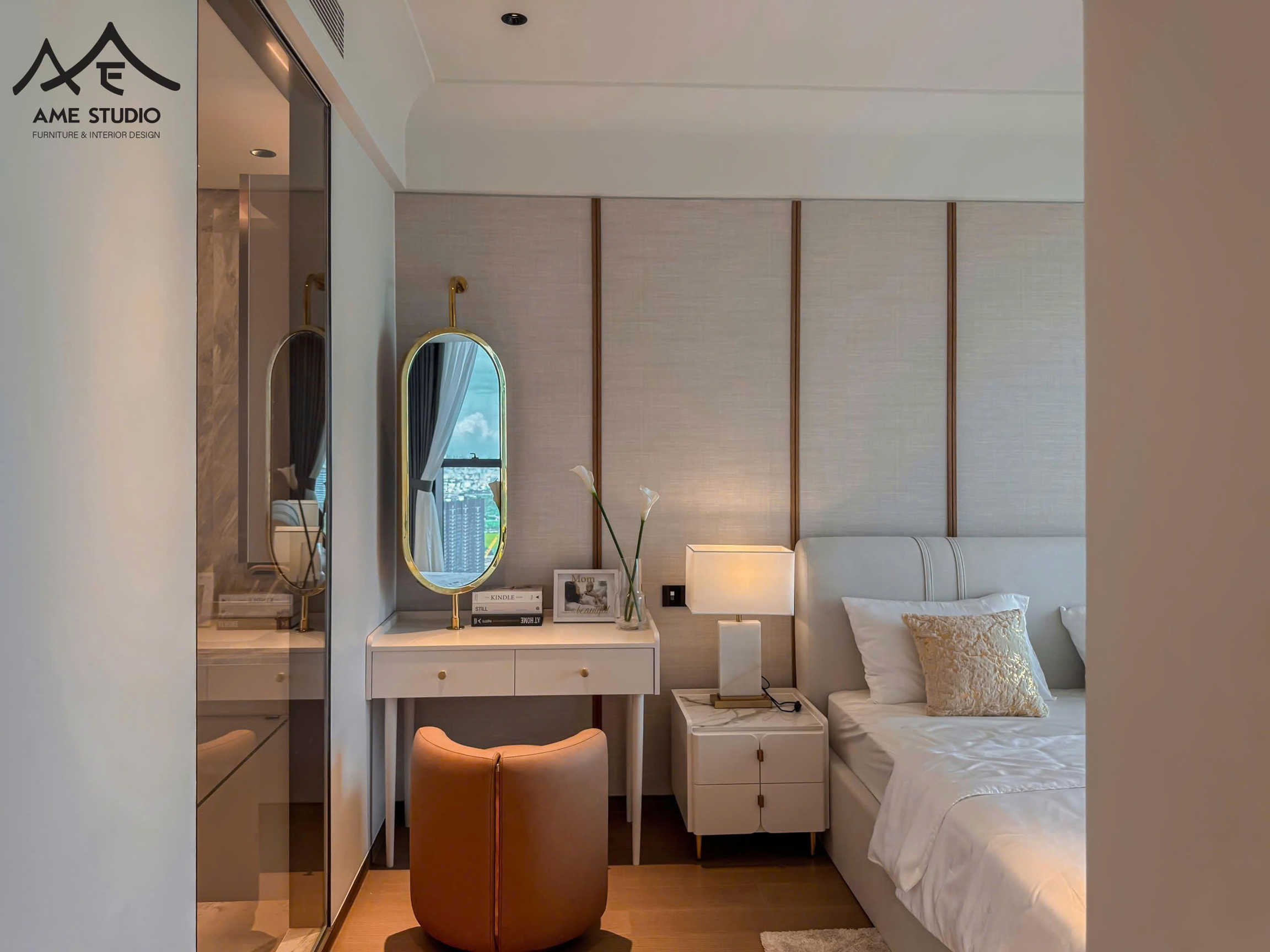 Phòng ngủ hiện đại với giường bọc nệm trắng, bàn trang điểm gương oval và ghế da nâu sang trọng
