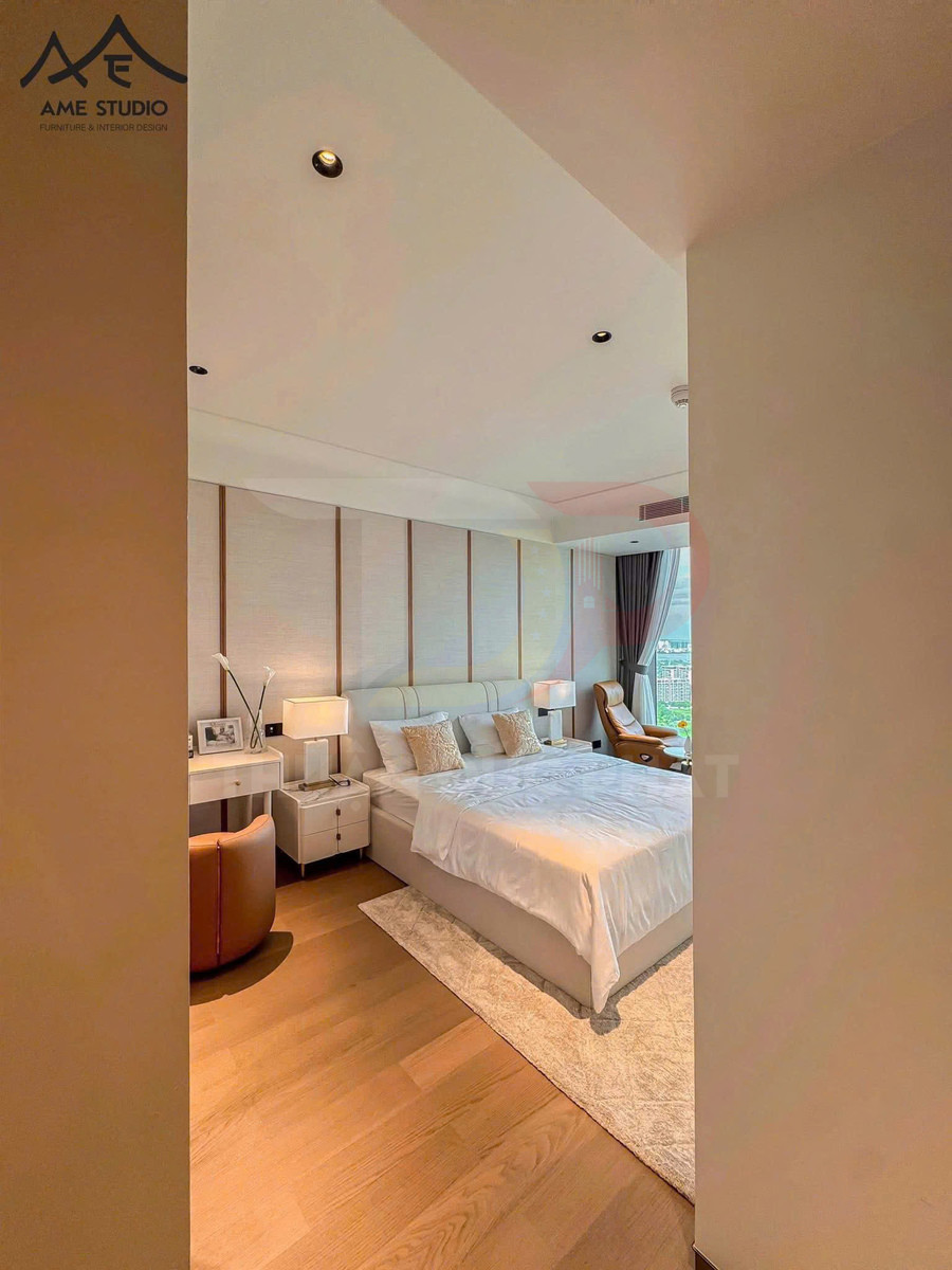 Phòng ngủ hiện đại với giường đôi bọc nệm, tủ đầu giường và ghế thư giãn cạnh cửa sổ lớn