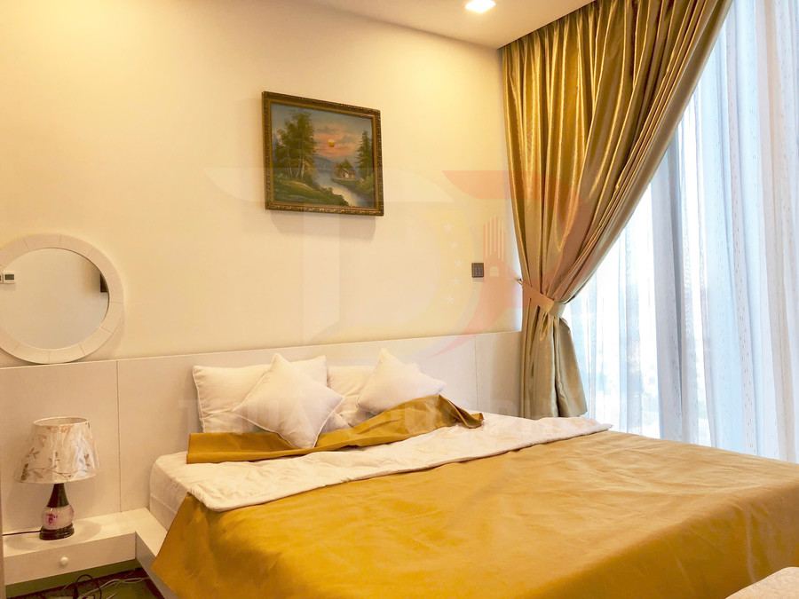 Phòng ngủ với giường đôi ga vàng, gối trắng, rèm cửa lớn và đèn ngủ trên tab đầu giường