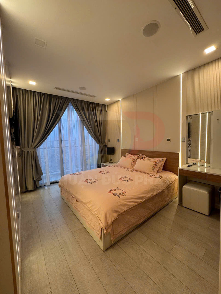 Phòng ngủ hiện đại với giường đôi ga màu hồng pastel, rèm cửa lớn và bàn trang điểm gọn gàng
