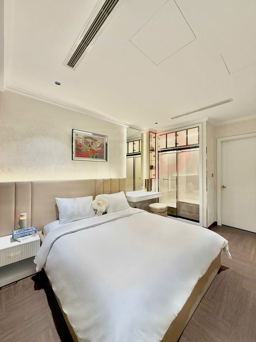 Phòng ngủ hiện đại với giường đôi ga trắng, táp đầu giường và bàn trang điểm cạnh cửa kính