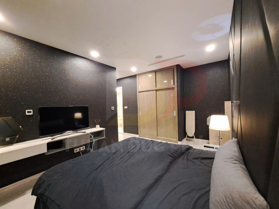 Phòng ngủ hiện đại với giường đôi bọc nệm, tủ quần áo gỗ cửa trượt và tivi màn hình phẳng treo tường