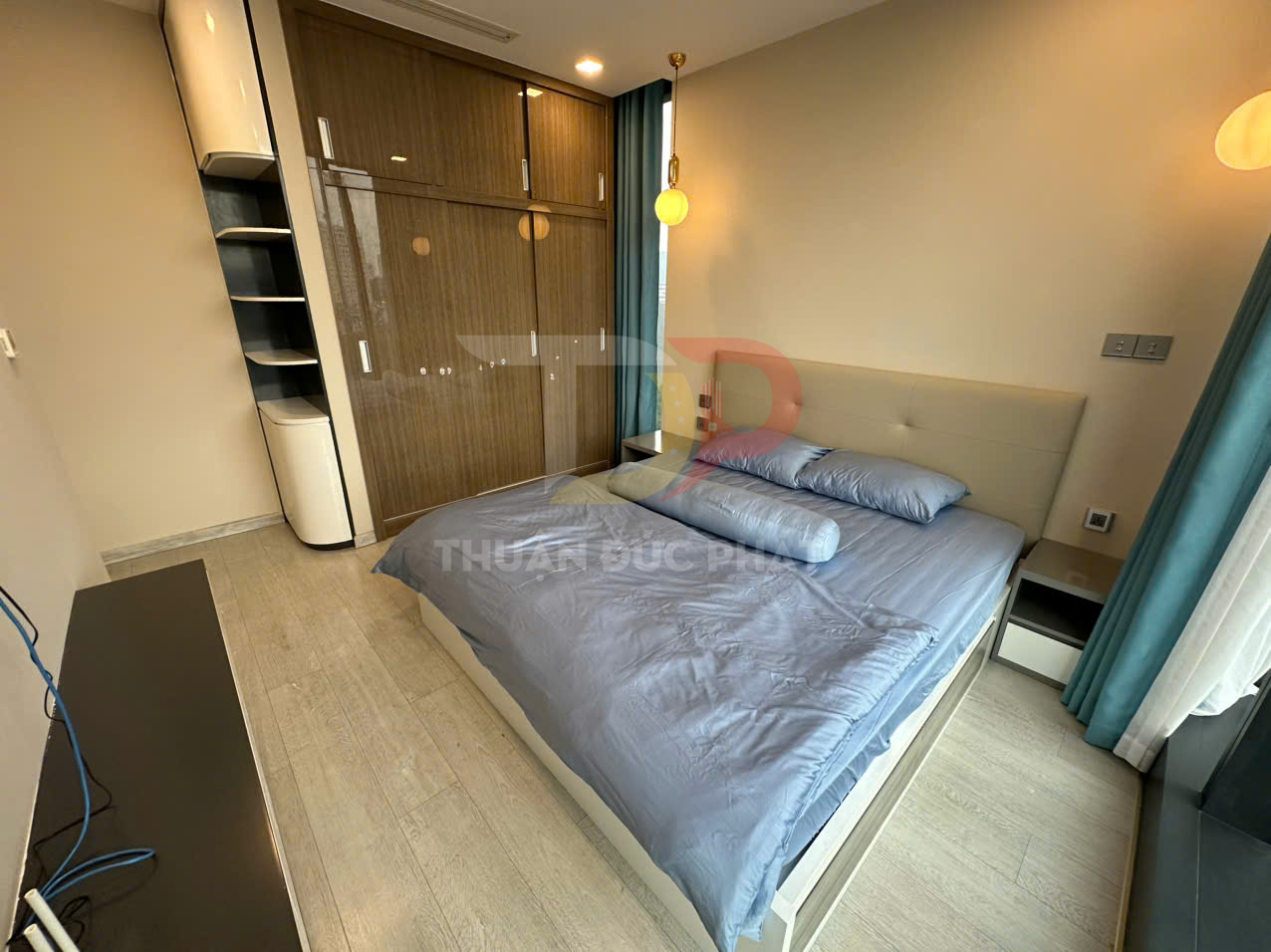 Phòng ngủ hiện đại với giường đôi bọc nệm ga xanh và tủ quần áo gỗ cửa lùa