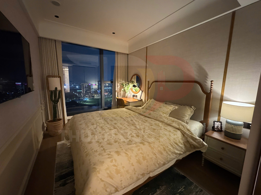 Phòng ngủ ấm cúng với giường đôi chăn ga hoa, cửa kính lớn nhìn ra thành phố về đêm