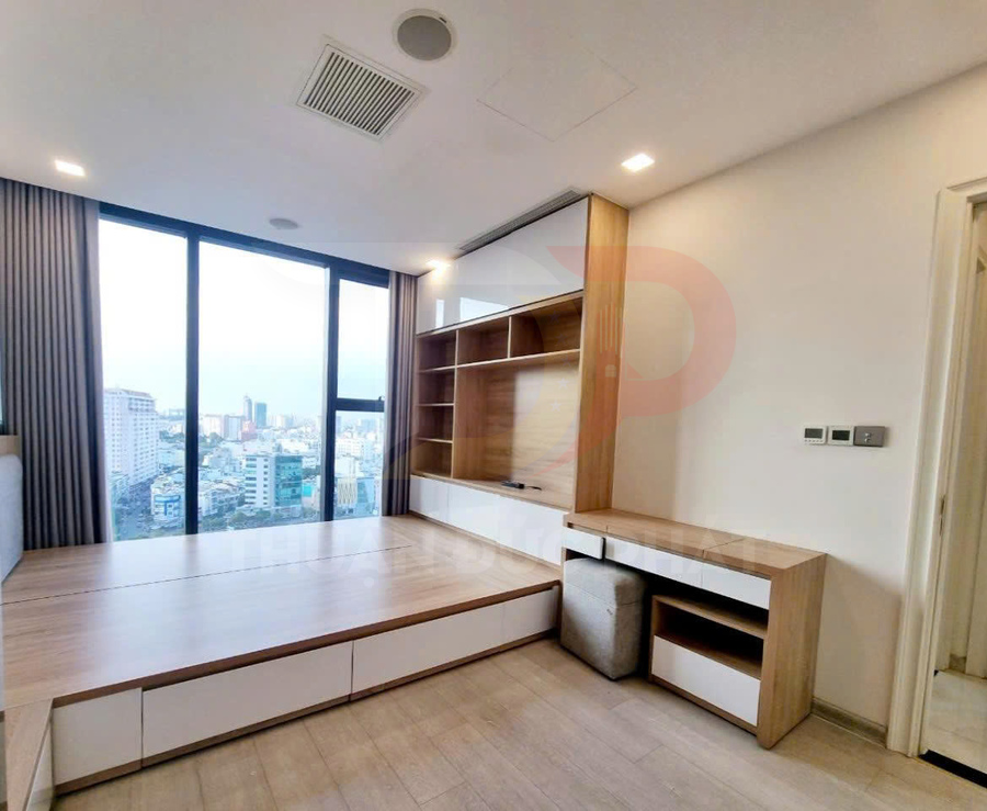 Phòng ngủ chung cư hiện đại với giường gỗ liền tủ kéo và kệ tivi âm tường cạnh cửa sổ kính lớn view thành phố