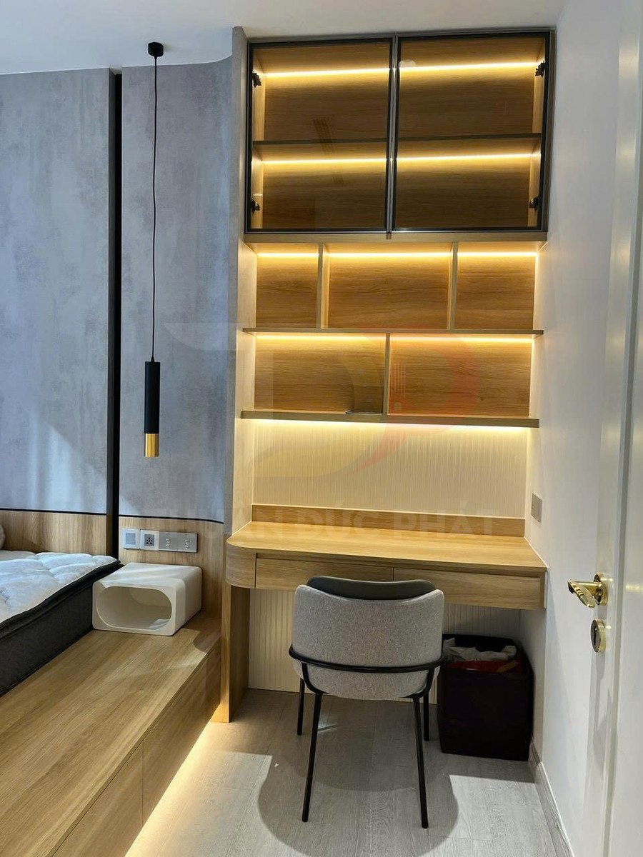 Bàn làm việc gỗ nhỏ gọn trong phòng ngủ hiện đại với kệ treo tường và đèn LED hắt sáng