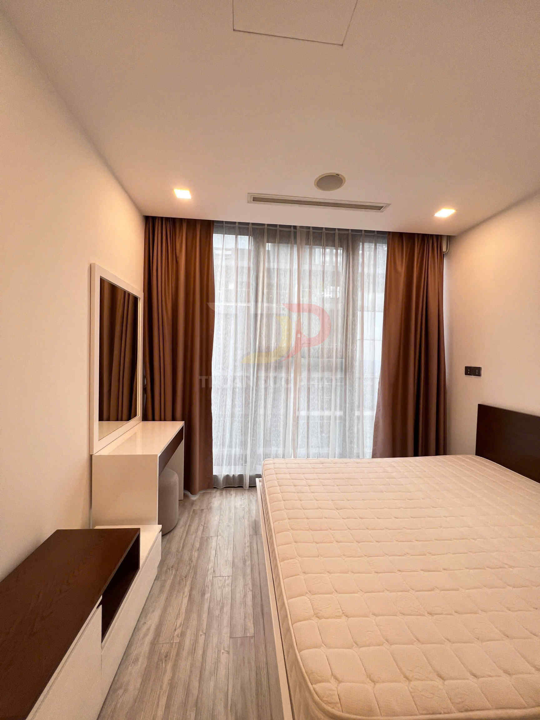Phòng ngủ hiện đại với giường nệm lớn, sàn gỗ, bàn trang điểm và rèm cửa sổ dài màu nâu